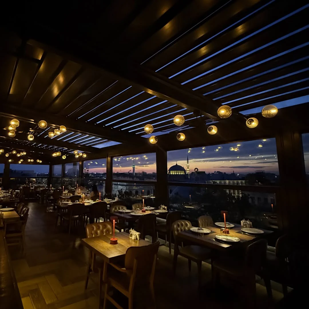 Window-side tables at Loti Roof Lounge overlooking Istanbul’s historic skyline at sunset