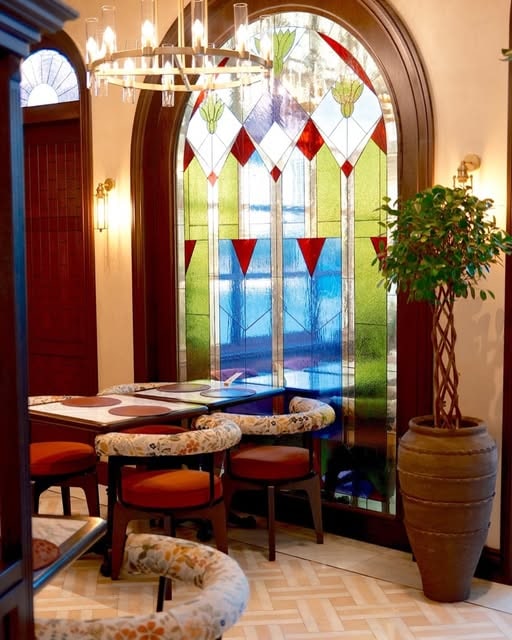 Noi Crea interior with stained glass and warm seating corners at Noi Crea